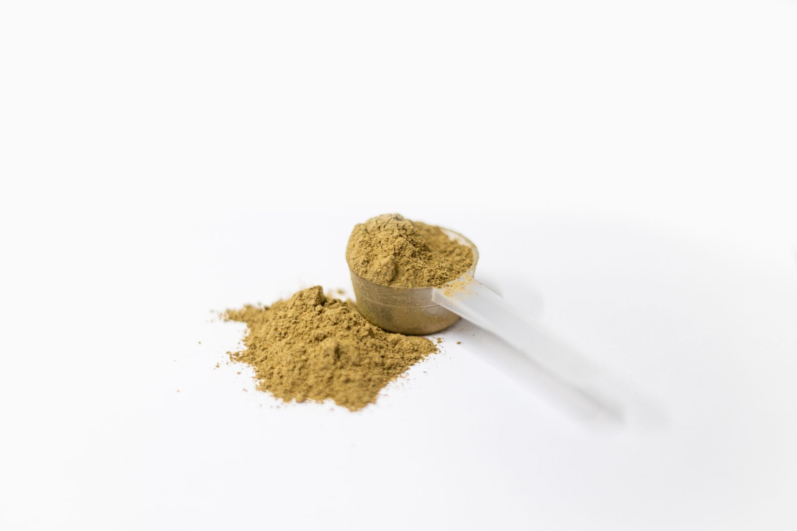 A heaped scoop of powder blend beside a pile of powder